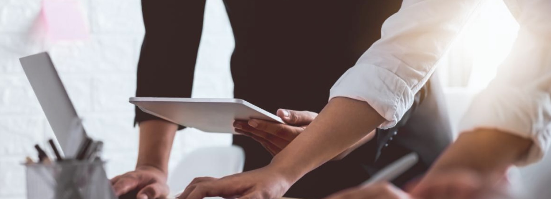 Ansicht von Händen mehrerer Menschen an einem Schreibtisch